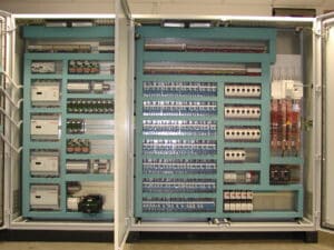 Armoire électrique industrielle ouverte, intérieur organisé avec automates PCD, disjoncteurs, borniers et câblage complexe.