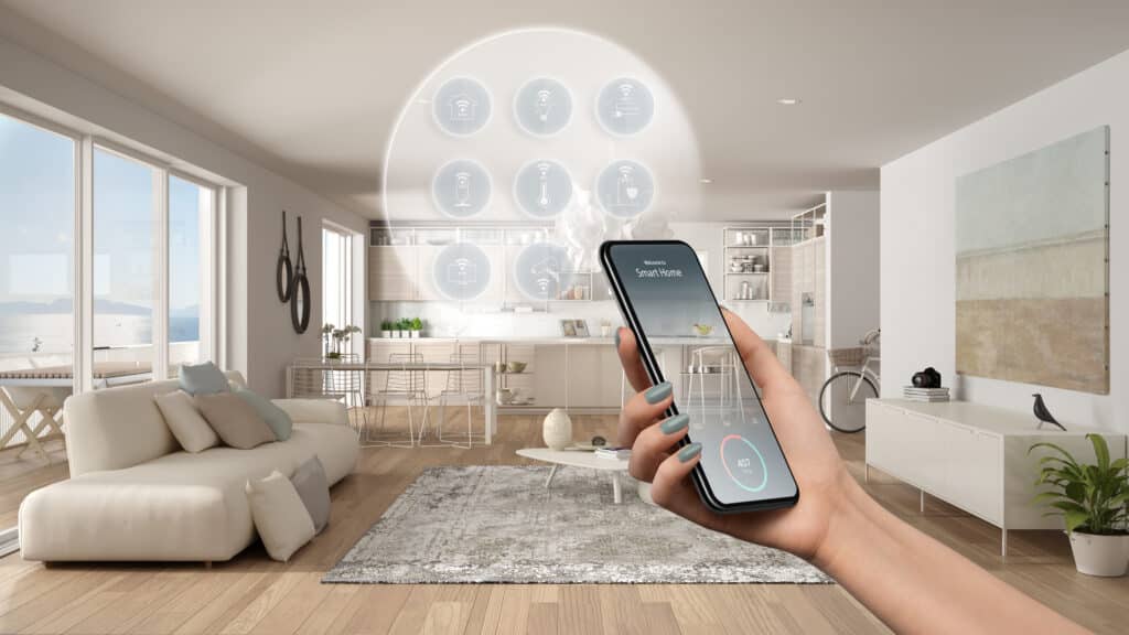 Main contrôle smartphone « Welcome to Smart Home », gérant salon-cuisine moderne vue mer. Icônes Wi-Fi affichent dispositifs intelligents.